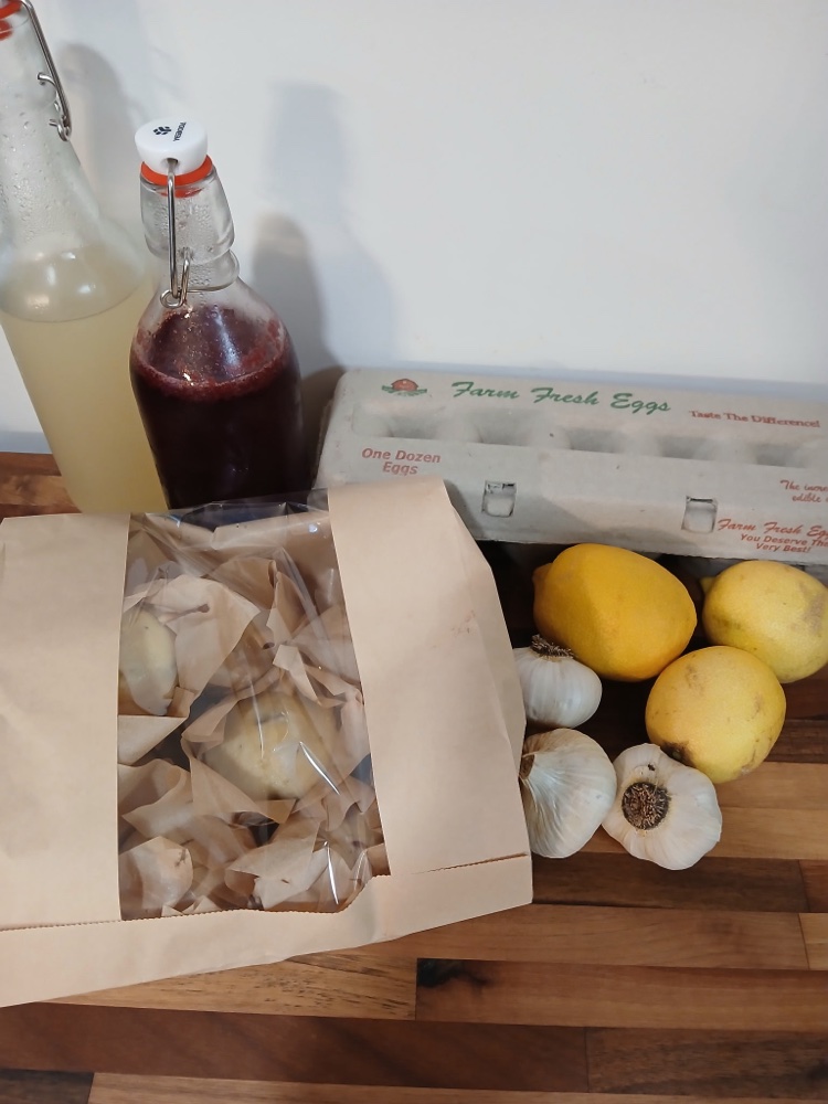 A Seasonal Produce Box from Solid Rock Homestead 725 with sourdough, eggs, lemons, garlic, and probiotic drinks